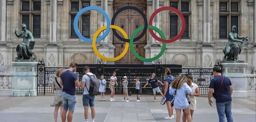 Des touristes devant les anneaux olympiques à Paris